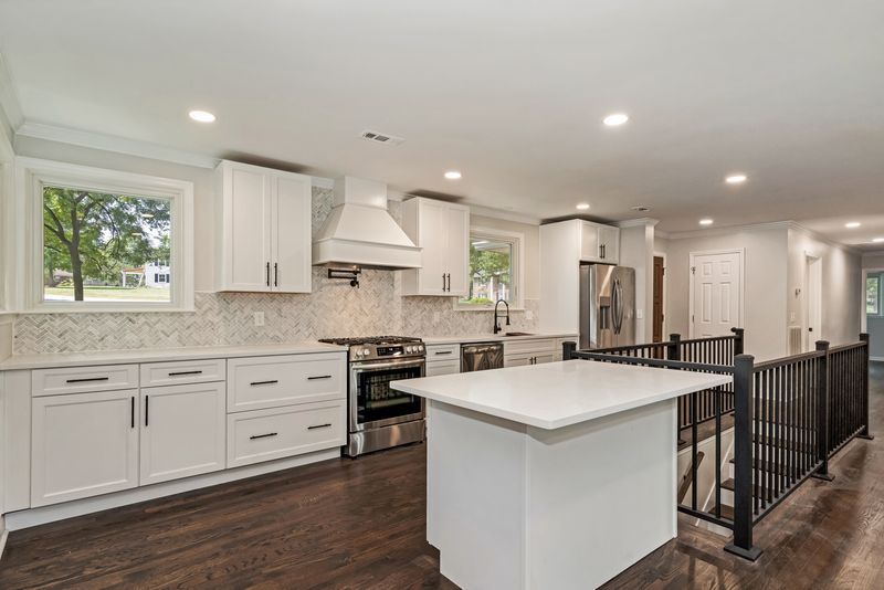 Anchorage Dr kitchen after — white shaker cabinets, herringbone backsplash, quartz island