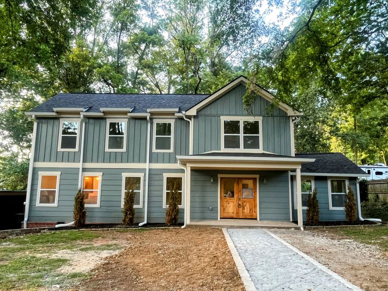 Log Cabin Rd exterior after — modern blue-green siding, new porch, wood door