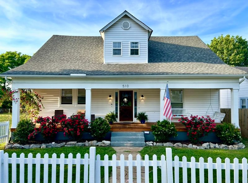 Timmons St exterior after — white picket fence, lush landscaping, charming cottage