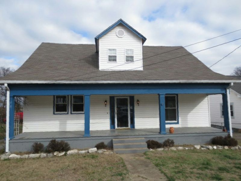 Timmons St exterior before — dated blue trim, worn porch, bare yard