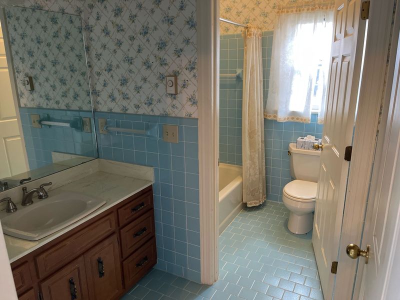Windemere Woods bathroom before — blue tile, floral wallpaper, dated vanity